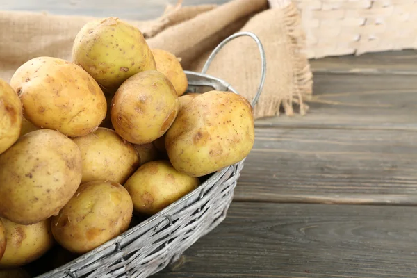 Unga potatis i rotting korg på träbord nära håll — Stockfoto