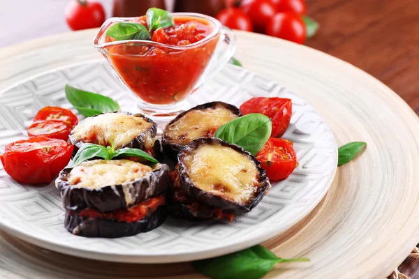 Prato de berinjela com tomates cereja e queijo em placa branca sobre mesa de madeira, close-up — Fotografia de Stock