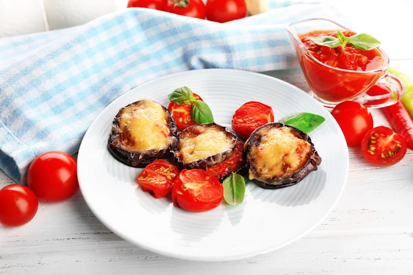 Plat d'aubergines aux tomates cerises et fromage en assiette blanche sur table en bois, gros plan — Photo
