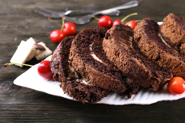 Läckra choklad rulla i vit platta på trä bakgrund — Stockfoto