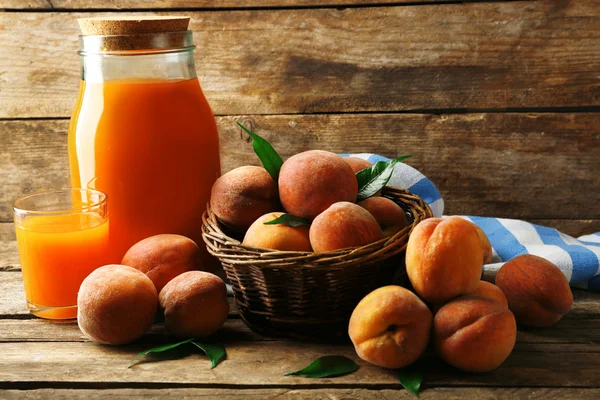 Mogna persikor och juice i glas på trä bakgrund — Stockfoto