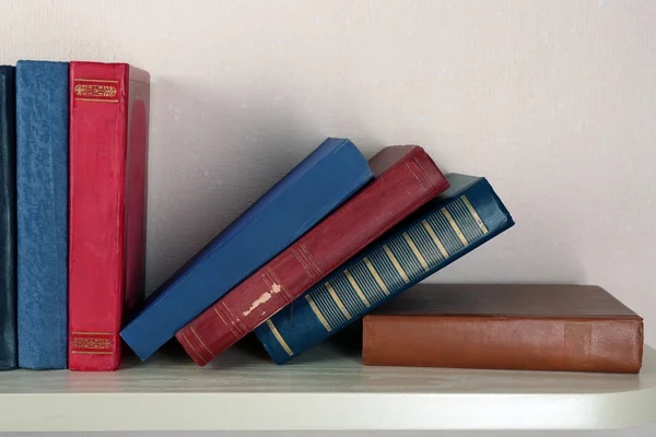 Livros antigos na prateleira, close-up, no fundo da parede de luz — Fotografia de Stock