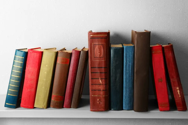 Oude boeken op plank, close-up, op lichte muur achtergrond — Stockfoto