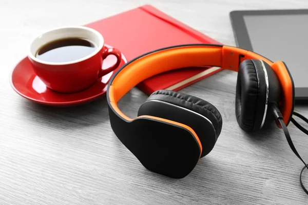 Fones de ouvido com tablet e xícara de café na mesa de madeira de perto — Fotografia de Stock