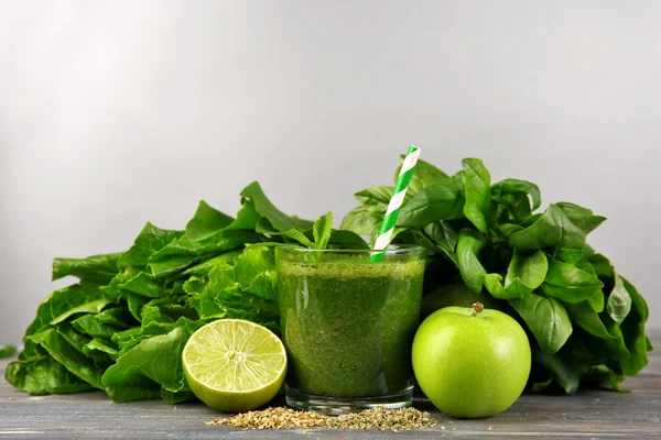 Succo sano verde con frutta ed erbe su sfondo grigio — Foto Stock