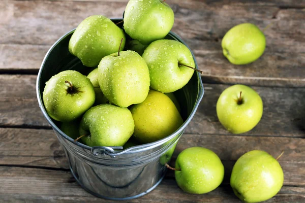 Zralé zelené jablko v plechový kbelík na dřevěný stůl zblízka — Stock fotografie