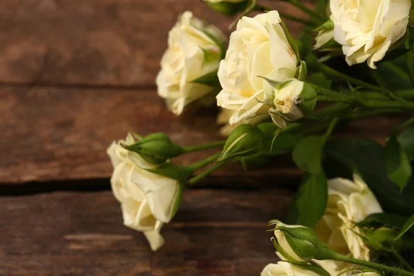 Lindas rosas pequenas na mesa de madeira de perto — Fotografia de Stock