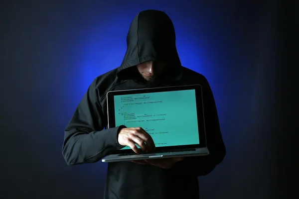 Hacker com computador e laptop sobre fundo escuro colorido — Fotografia de Stock