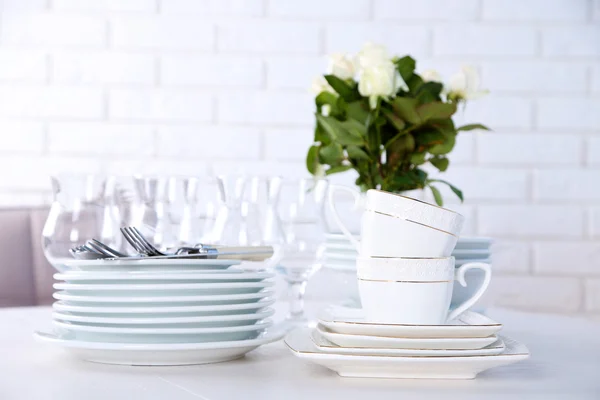 Tiszta tányérok, poharak és evőeszközök a fehér asztal — Stock Fotó