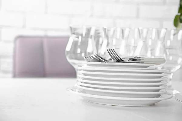 Clean plates, glasses and cutlery on white table