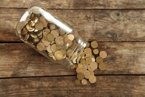 Coins in money jar on wooden background — Stock Photo, Image