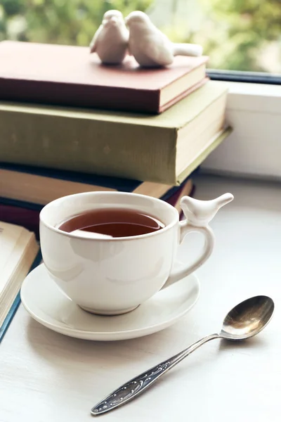 Bardak çay ile pencere, closeup üzerinde kitap yığını — Stok fotoğraf