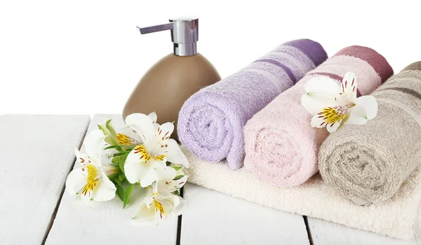 Miękkie ręczniki z dozownika i kwiaty na jasnym tle — Zdjęcie stockowe