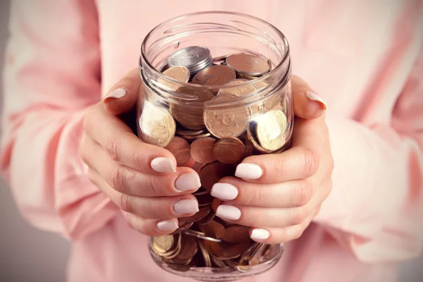 Mujer sosteniendo el frasco de dinero con monedas de cerca —  Fotos de Stock