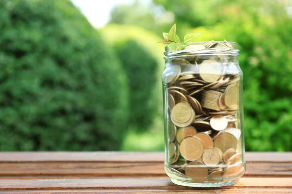 Coins in money jar on table outdoors — Stock Photo, Image