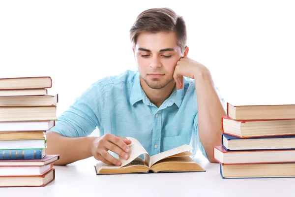 Junger Mann liest Buch am Tisch auf weißem Hintergrund — Stockfoto