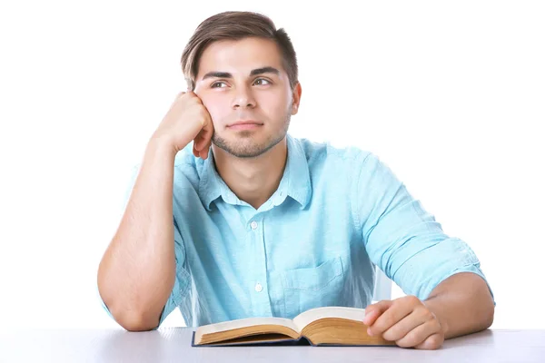 Jonge man leesboek aan tafel op witte achtergrond — Stockfoto