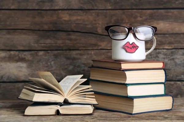 Винтажные книги и чашка с губами на деревянном фоне — стоковое фото