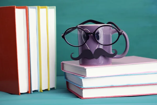 Boeken en cup met snor op kleurrijke achtergrond — Stockfoto