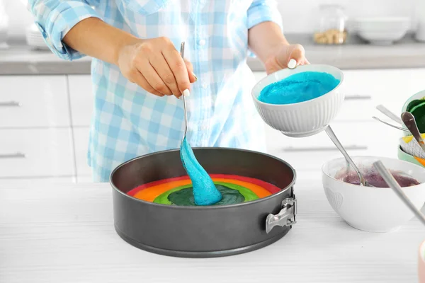 Young woman making rainbow cake in kitchen — Stock Photo, Image