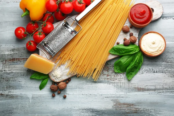 Těstoviny špagety s rajčaty, sýrem a bazalkou na barevné dřevěné pozadí — Stock fotografie