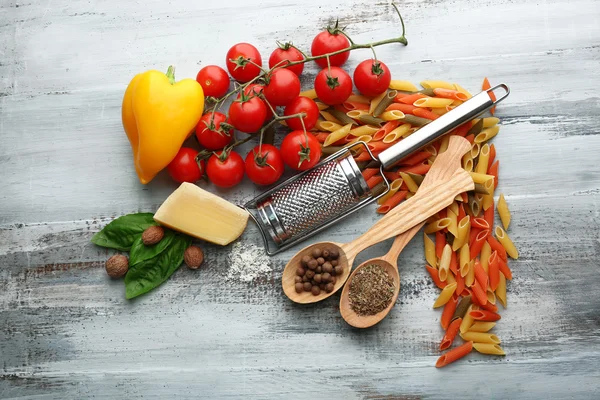 Penne de pasta con tomates, queso y albahaca sobre fondo de madera de color —  Fotos de Stock