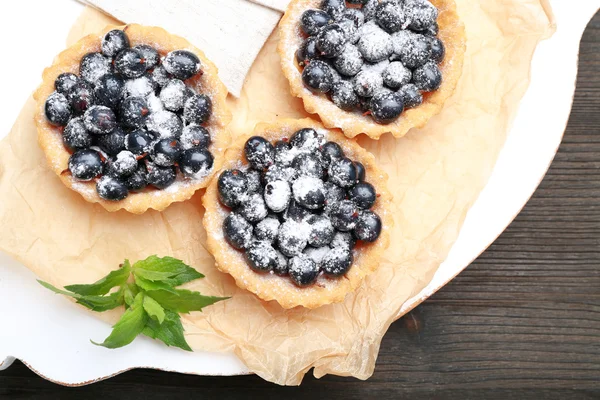 Deliziose crostate croccanti con ribes nero su pergamena su tavola di legno, vista dall'alto — Foto Stock