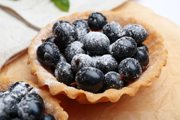 Delicious crispy tart with black currants on parchment, closeup — Stock Photo, Image