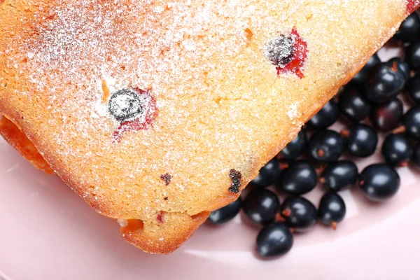 Pastel recién horneado con grosellas negras en plato rosa, primer plano — Foto de Stock