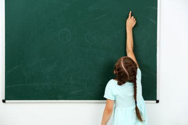 Küçük kız kara tahta üzerinde bir şey işaret