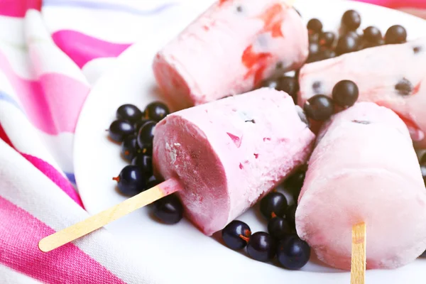 Helado dulce con grosellas negras en plato blanco sobre servilleta rayada, primer plano — Foto de Stock