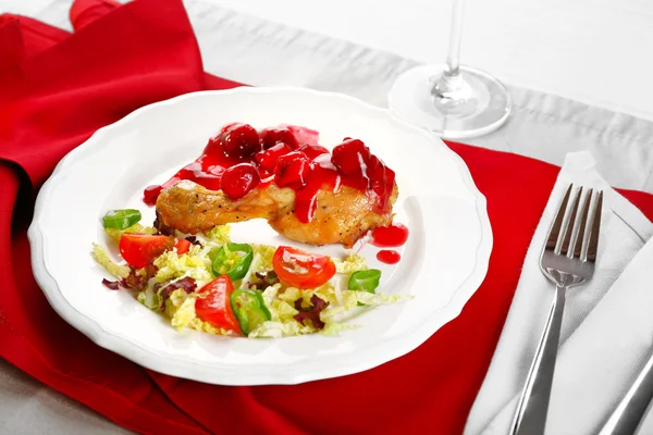 Gerecht van gebakken kip been en fruit salade met witte plaat met glas wijn op tafel met servet, close-up — Stockfoto