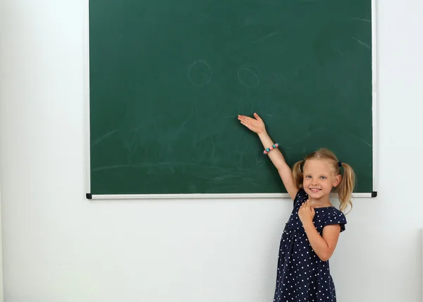 Malá holčička na něco, co je na tabuli — Stock fotografie