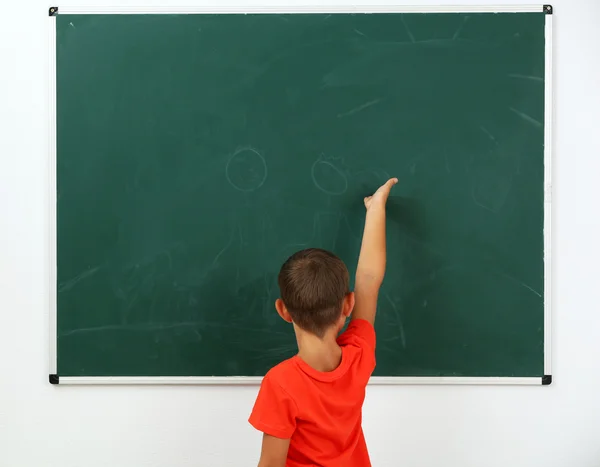 Little boy pointing at something on chalkboard — Stock Photo, Image