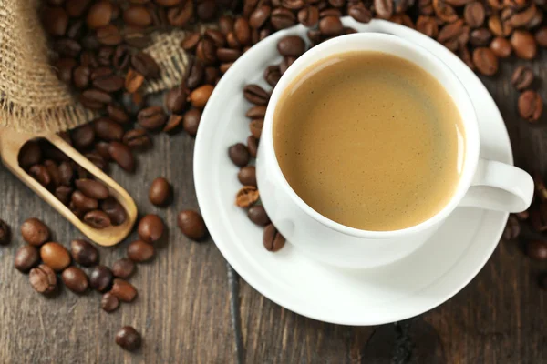 Cup of coffee with beans on table close up — Stock Photo, Image