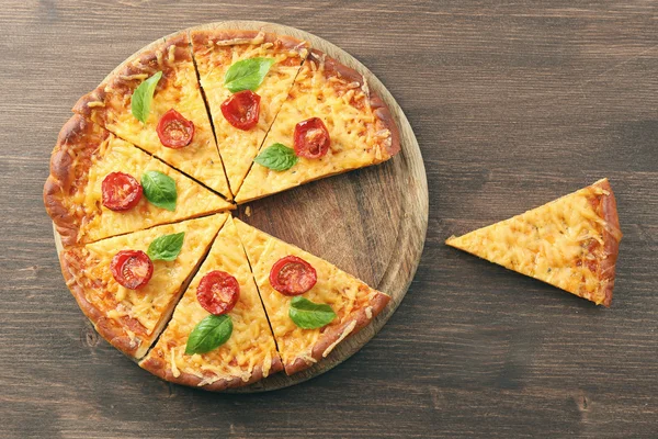 Fette di gustosa pizza al formaggio con basilico e pomodorini sul tavolo da vicino — Foto Stock