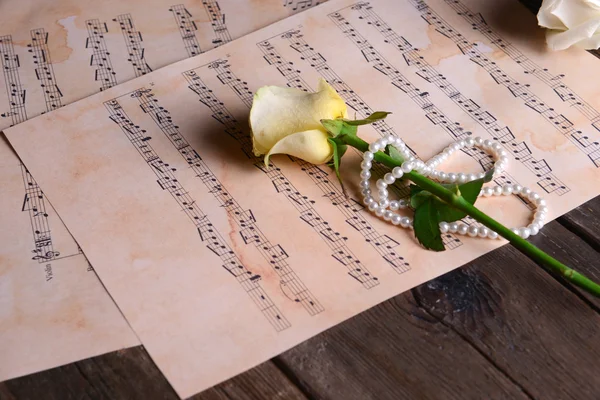 Schöne Rose mit Perlen auf Notenblättern — Stockfoto