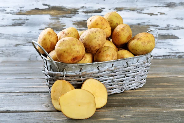 Batatas jovens em cesta de vime no fundo de madeira — Fotografia de Stock