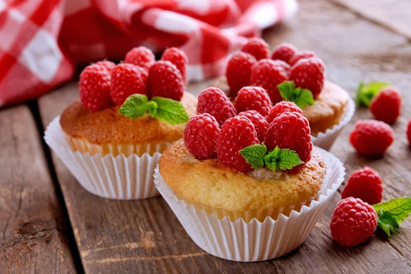 Deliciosos cupcakes con bayas y menta fresca en la mesa de madera de cerca —  Fotos de Stock