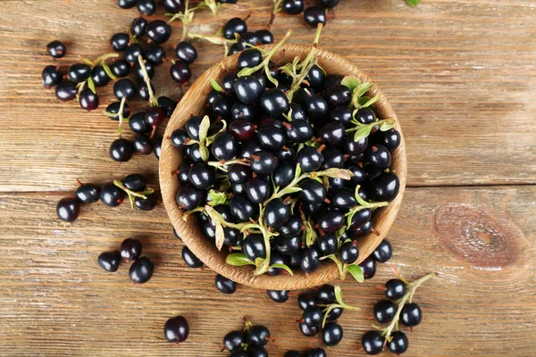 Fresh black currants in bowl on wooden table, top view — Stock Photo, Image