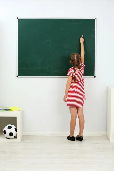 Niña apuntando a algo en pizarra — Foto de Stock