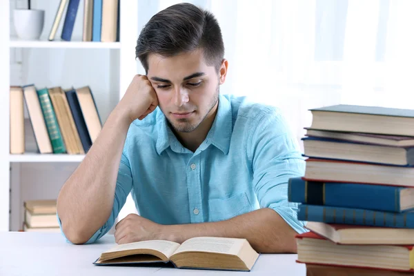 Jonge man leesboek aan tafel Stockfoto