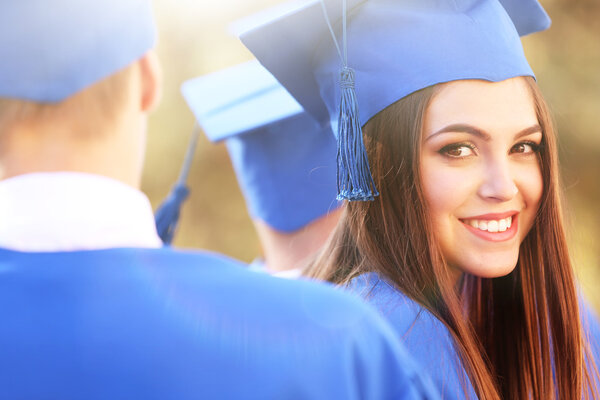 Graduated students in graduation hats and gowns, outdoors