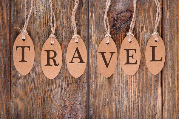 Travel incription on brown tags on wooden background