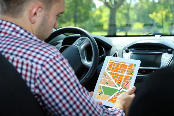 Man sitting in the car and holding tablet pc with map gps navigation application