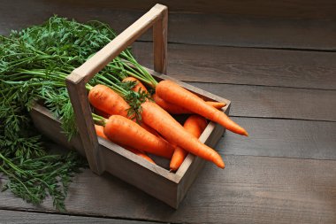 Ahşap arka plan üzerinde sandık içinde taze organik havuç