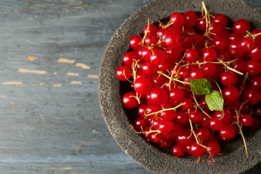 Olgun kırmızı kuş üzümü kase ahşap arka plan üzerinde