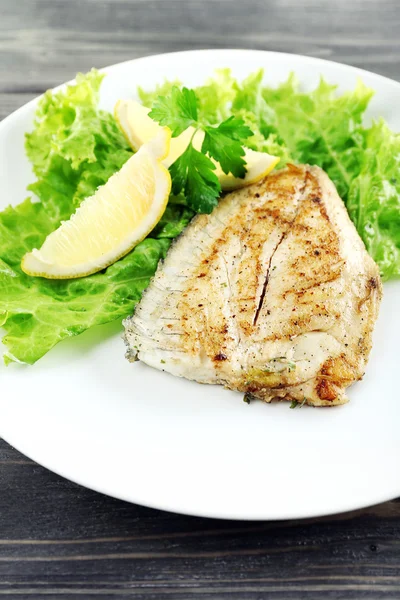 Maträtt av fiskfilé med sallad och citron på bordet på nära håll — Stockfoto