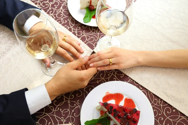 Hands of newlyweds at table