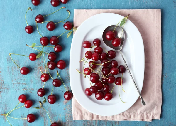 Cerises douces sur assiette, sur fond bois — Photo